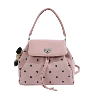 Front view of pink polka-dot fabric, heart-shaped clasp, top handle, shoulder strap and plush charm