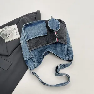 Flat lay of distressed blue and charcoal denim panels with a round coin pouch and striped charm