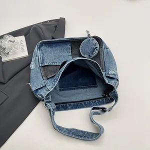 Top-down view of an open patchwork denim bag, showing its roomy interior, coin pouch and strap