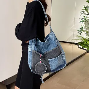 Model wearing a two-tone denim shoulder bag with patch pockets and a matching round coin pouch