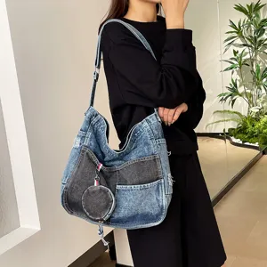 Model wearing a blue washed denim shoulder bag with gray patchwork pocket and round coin purse charm