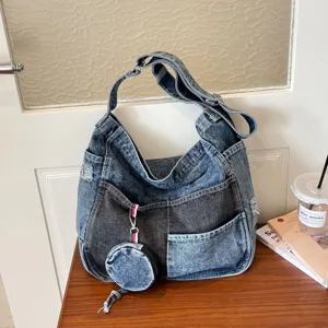 Large washed-blue denim shoulder bag with distressed patchwork, wide strap and round coin pouch