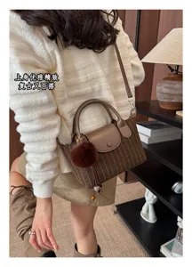 Borsa a righe marroni indossata, con patta in pelle, pon pon morbido e lunga tracolla regolabile