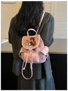 Rear view of a person wearing a pink suede backpack with a teddy bear flap and leather pockets