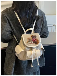 Back view of a model wearing a cream suede backpack with teddy bear patches and bow details