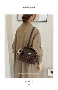 Back view of a model wearing a brown dotted flap shoulder bag with heart clasp and bear charm