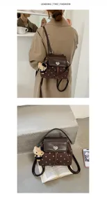 Back view and tabletop display of a brown polka-dot bag with heart clasp and plush charm