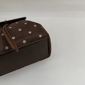 Close-up of a brown bag with pale polka dots, dark faux-leather base and matching trim