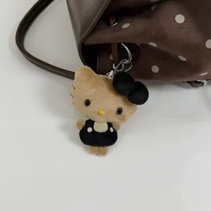 Close-up of a plush cat charm in a black dress and bow, hanging from a brown polka-dot bag
