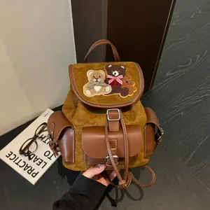 Brown faux-suede backpack with teddy bear appliqués, a leather flap and buckle pockets