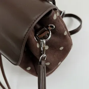 Close-up of a brown dotted faux-suede bag with a leather flap and silver strap clasp
