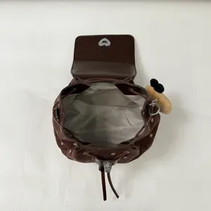 Top view of the open bag reveals gray fabric lining, brown dotted sides and a plush bear charm