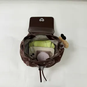 Top-down view of an open brown dotted backpack showing its roomy interior and teddy bear charm