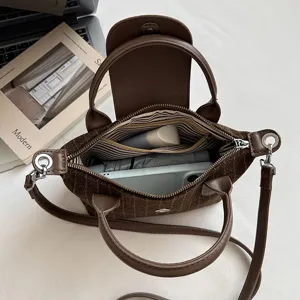 Vue de dessus d’un sac marron à carreaux ouvert, avec doublure rayée et effets personnels visibles