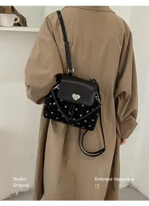 Back view of a person wearing a black dotted velvet bag with a heart-shaped clasp