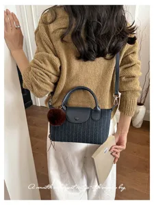 Vista posteriore di donna con borsa blu a righe, dettagli in pelle nera e pompon in pelliccia