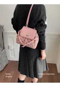 Model wearing a pink black-dotted bag with heart clasp and adjustable strap, shown crossbody
