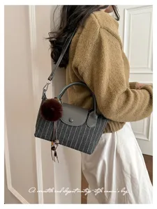 Borsa a righe sottili grigie indossata dalla modella, con patta scura, pon pon e nappa pendente