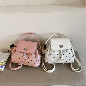 Small pink and ivory convertible backpacks with black polka dots, heart clasps and bear charms