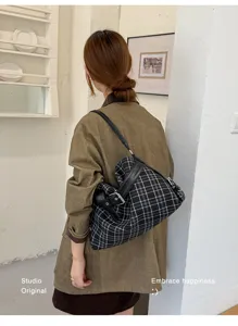 Back view of a woman carrying a black plaid shoulder tote with leather strap and metal buckle