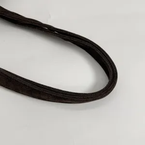 Primer plano de un asa curva de tela marrón oscuro, con superficie suave y borde trenzado