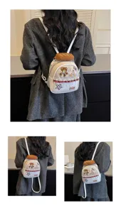 White mini backpack shown from behind, with teddy patch, bread-shaped charm and red gingham trim