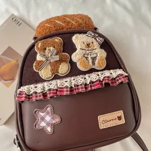 Close-up of teddy bear patches, plaid bow, lace trim and star appliqué on a brown bag