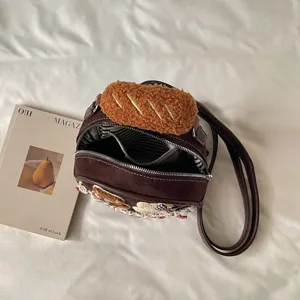 Close-up of the open brown bag, showing striped lining, zipper, plush bread charm and floral trim