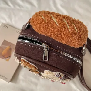 Close-up of a brown suede bag with a plush bread-shaped top, zipper and fabric appliqués