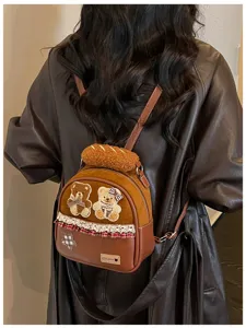 Back view of a person wearing a brown mini backpack with teddy bear patches, lace and plaid trim.
