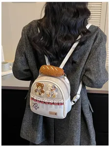 Back view of a model wearing a pale gray backpack with teddy bear, plaid bow and lace trim
