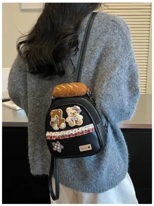Black mini bag on a gray sweater, with teddy patches, plaid lace trim and a plush handle
