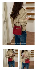 Lifestyle view of a burgundy suede-look bucket bag with braided handle and gold clasp worn crossbody