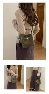 Lifestyle view of a model carrying a green suede-look bucket bag with braided handle and bead charm
