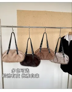 Vier flauschige Kunstfelltaschen in Beige, Dunkelbraun, Karamell und Grau hängen am Metallständer