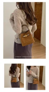 A brown suede-look bucket bag with woven handle and gold clasp, worn over the shoulder