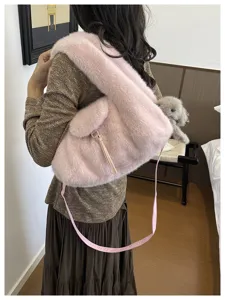Model wearing a plush pink shoulder bag, with a long matching strap and zipper detail visible