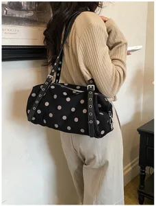 Back view of a model carrying a black bag with white dots, studded straps and silver hardware