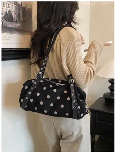 Rear view of a model carrying a black bag with white dots, leather straps and silver hardware