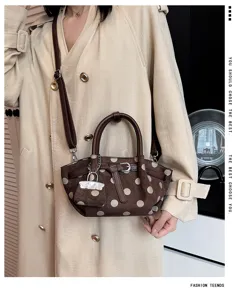 Modella con borsa marrone a pois, manici e tracolla in pelle, abbinata a un trench beige