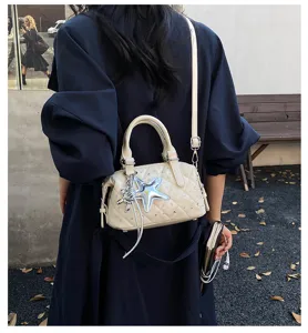 Vista da dietro di una persona con borsa trapuntata color crema, stella argentata e tracolla lunga