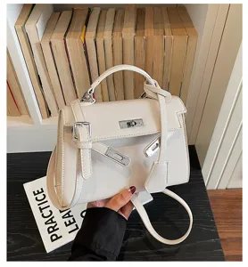 Borsa color crema tenuta in mano, con chiusura argentata, manico superiore e tracolla removibile