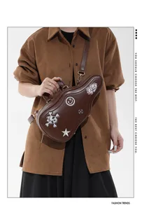 Personne portant un sac brun en forme de guitare, avec des patchs brodés et une bandoulière réglable