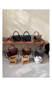 Sei piccole borse in vari colori, esposte con tracolle e morbidi ciondoli a pompon decorativi