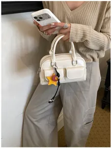 Persona con una piccola borsa bianca, doppi manici, tasche frontali con patta e ciondoli colorati