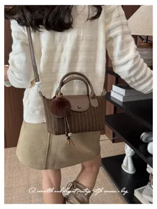 Borsa a spalla a righe marroni con patta in pelle, pompon e nappina indossata da una modella