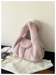 Close-up of a soft pink faux-fur bag with a flap, plush handles and a dangling metal charm