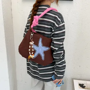 Borsa marrone con stella marina blu, tracolla rosa intrecciata e nappa di perline in legno a spalla