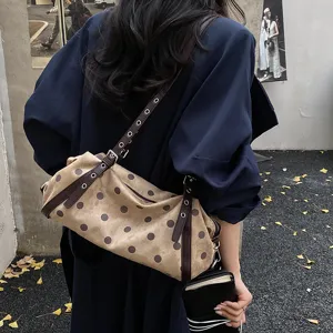 Vintage beige polka dot shoulder bag with brown leather strap and metal eyelets, worn on shoulder