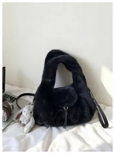 Close-up of a black plush half-moon bag with a faux-fur handle, metal ring and tassel